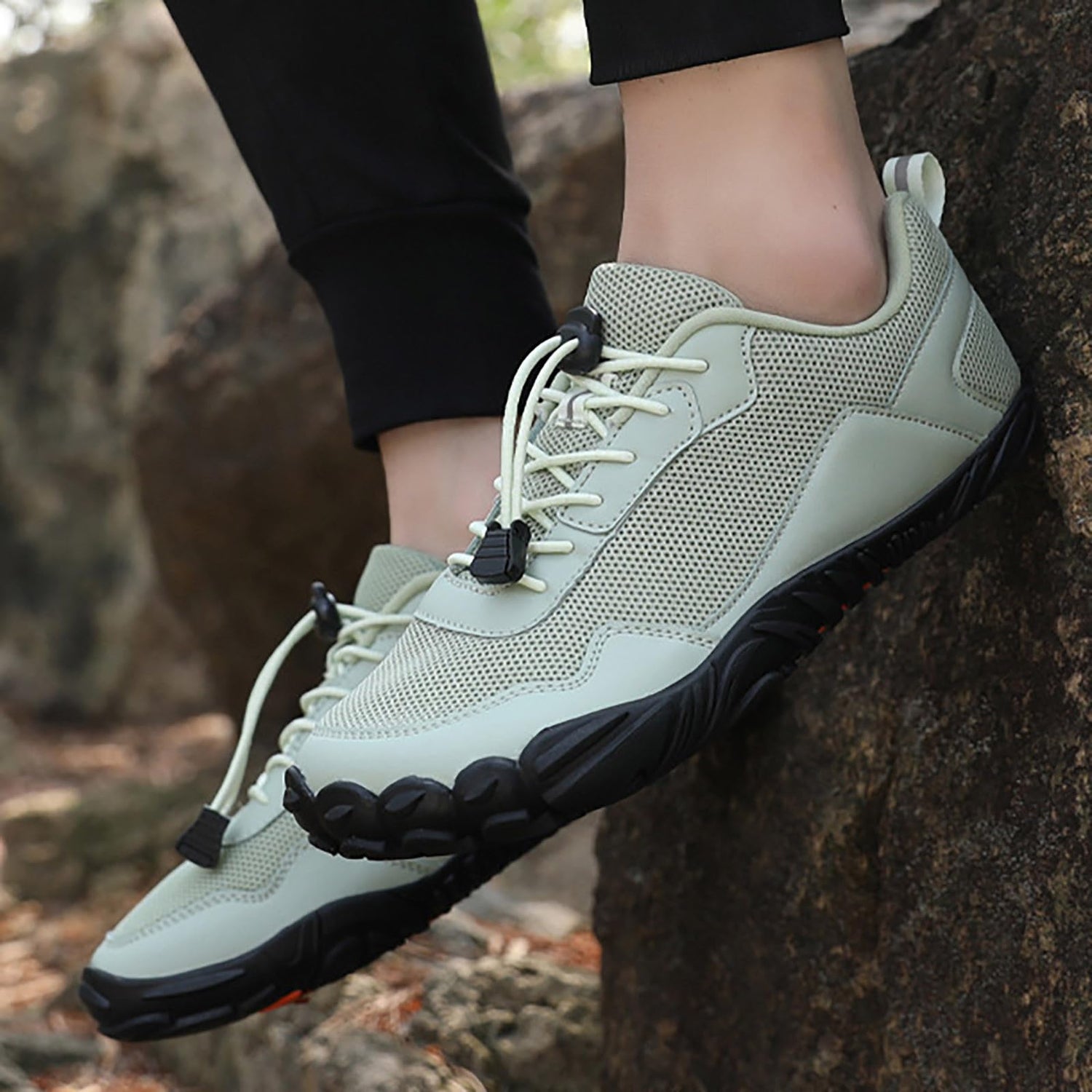 A person in sneakers balances on a rock - Joyo barefoot